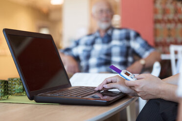 Ausgeschnittenes Bild einer Altenpflegerin, die mit Laptop und Kreditkarte in einem Pflegeheim Medikamente online kauft - MASF11143