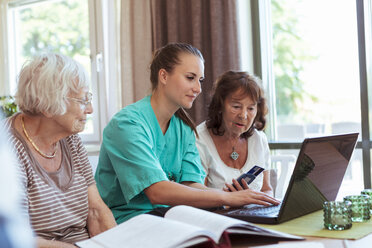 Nurse with senior women buying medicine online using laptop and credit card at nursing home - MASF11149