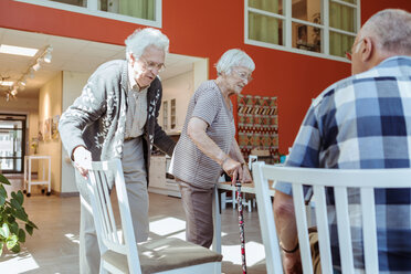 Älterer Mann zieht den Stuhl für eine Frau im Pflegeheim heraus - MASF11173