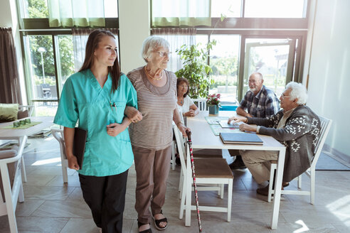 Junge Krankenschwester und ältere Frau gehen Arm in Arm im Pflegeheim - MASF11179