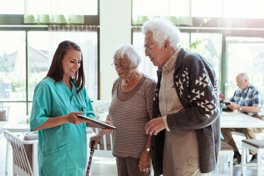 Junger Hausmeister zeigt Seniorenpaar im Pflegeheim digitales Tablet - MASF11191