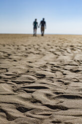 Wellenmuster am Strand mit Silhouette von Paar zu Fuß Hand in Hand im Hintergrund - JATF01122