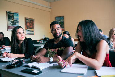 Multi-ethnische Freunde unterhalten sich am Schreibtisch im Klassenzimmer - MASF11239