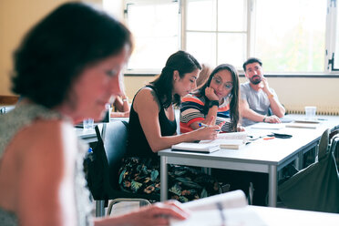 Students discussing over book at desk in classroom - MASF11243