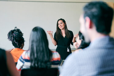 Happy teacher gesturing and explaining students in classroom - MASF11250