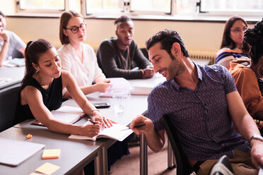 Multi-ethnic friends discussing over book in classroom - MASF11262