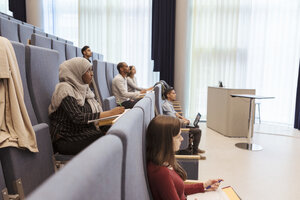 Male and female students studying while sitting in auditorium at university - MASF11294