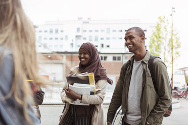 Smiling male and female students standing with friends at university campus - MASF11307