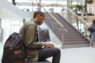 Junge Schülerin liest ein Buch, während sie im Korridor einer High School sitzt - MASF11309