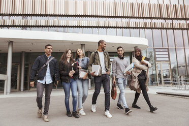 Studenten einer multiethnischen Universität laufen in voller Länge gegen ein Gebäude auf dem Campus - MASF11312