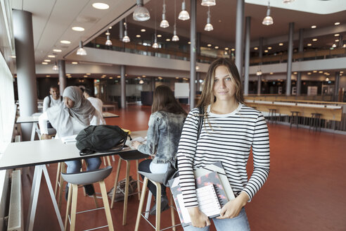 Porträt einer Universitätsstudentin in der Cafeteria mit Freunden im Hintergrund - MASF11346