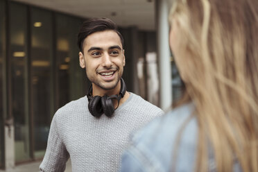 Lächelnder junger Mann im Gespräch mit einer Freundin auf dem Universitätscampus - MASF11348