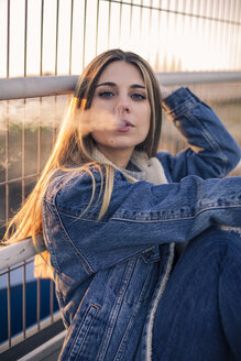 Portrait of young woman blowing out smoke - ACPF00465