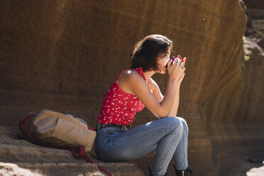 Spanien, Gran Canaria, Barranco de las Vacas, junge Frau, die sich ausruht und Wasser trinkt - KKAF03108
