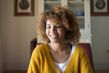 Portrait of smiling young woman with curly hair at home - KIJF02275