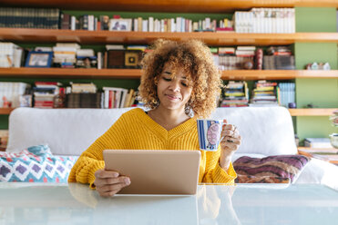 Young woman with curly hair using tablet at home - KIJF02277