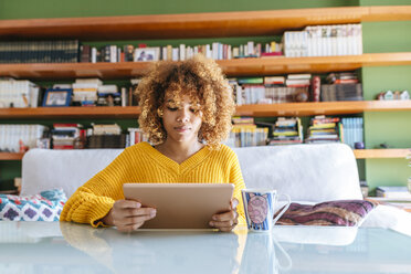 Young woman with curly hair using tablet at home - KIJF02278