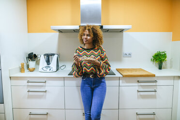 Young woman with curly eating cereals in kitchen - KIJF02293