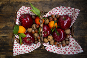 Weidenkorb mit roten Äpfeln, Mandarinen, Haselnüssen und Walnüssen - LVF07788