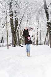 Glückliche Mutter, die mit ihrer Tochter in einer Winterlandschaft spazieren geht - DIGF05860