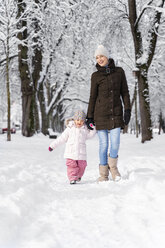 Happy mother walking with daughter in winter landscape - DIGF05861