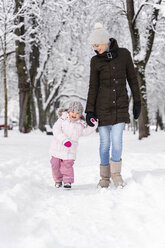 Happy mother walking with daughter in winter landscape - DIGF05862