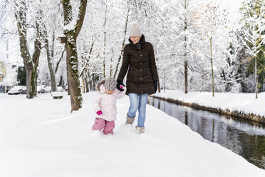 Happy mother walking with daughter at a moat in winter landscape - DIGF05863