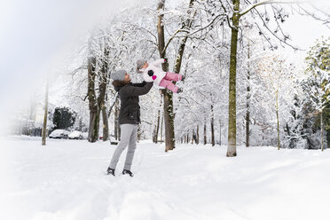 Glücklicher Vater spielt mit Tochter in Winterlandschaft - DIGF05864