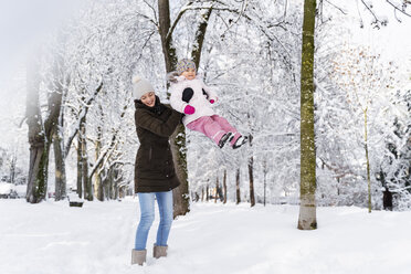 Glückliche Mutter spielt mit Tochter in Winterlandschaft - DIGF05866