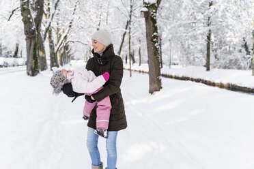 Glückliche Mutter spielt mit Tochter in Winterlandschaft - DIGF05867