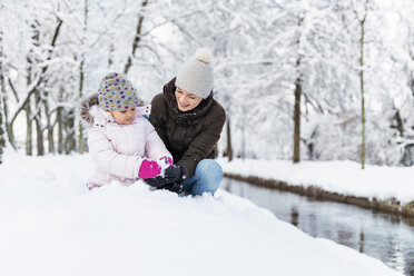 Happy mother with daughter at a moat in winter landscape - DIGF05871