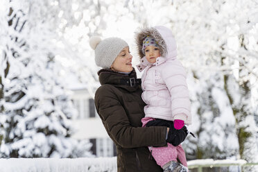 Happy mother carrying daughter in winter landscape - DIGF05877