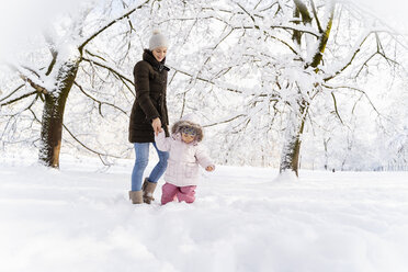 Glückliche Mutter, die mit ihrer Tochter in einer Winterlandschaft spazieren geht - DIGF05879