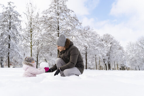 Glücklicher Vater spielt mit Tochter in Winterlandschaft - DIGF05888