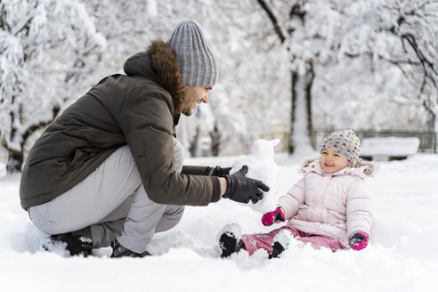 Glücklicher Vater spielt mit Tochter in Winterlandschaft - DIGF05889