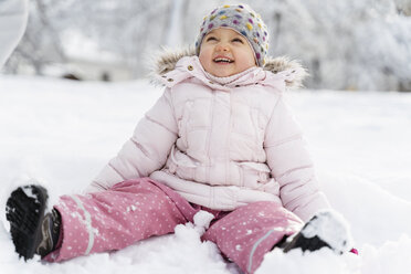 Niedliches kleines Mädchen sitzt im Schnee im Winter - DIGF05890