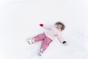 Cute little girl lying in snow in winter making a snow angel - DIGF05891