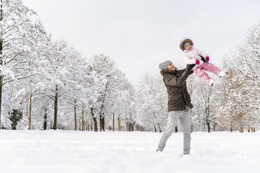 Glücklicher Vater spielt mit Tochter in Winterlandschaft - DIGF05892