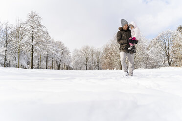 Father carrying daughter walking in winter landscape - DIGF05894