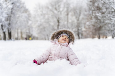 Niedliches kleines Mädchen sitzt im Schnee im Winter - DIGF05895