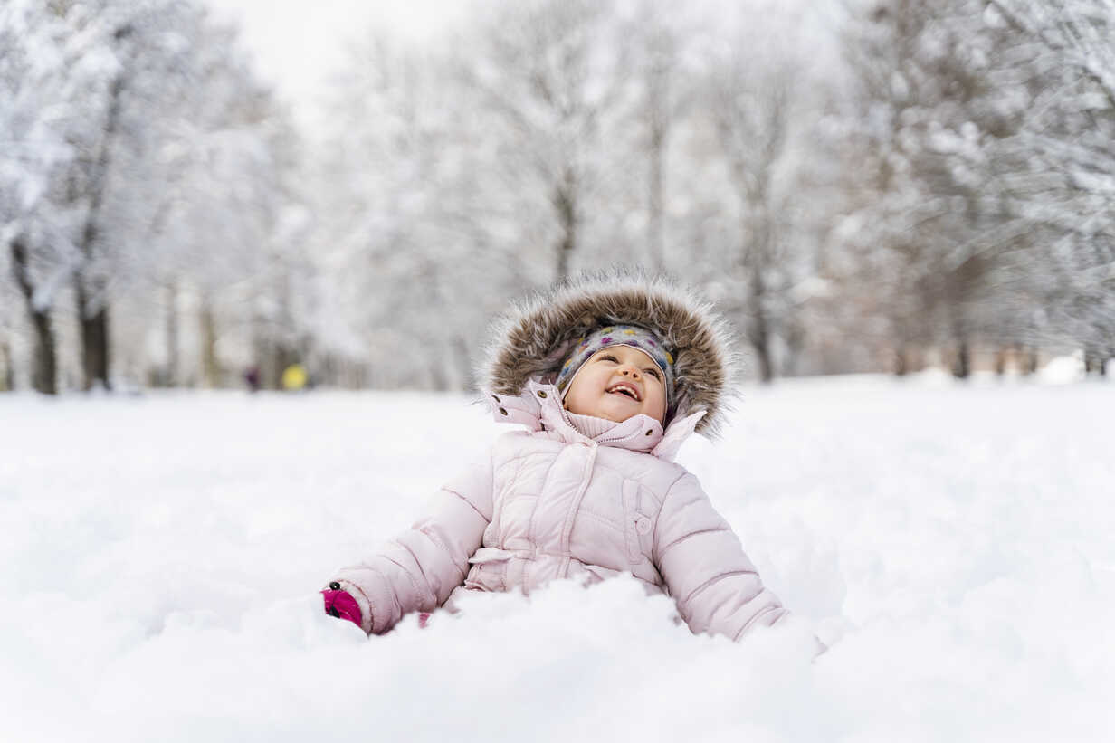 Cute little girl sitting in snow in winter stock photo