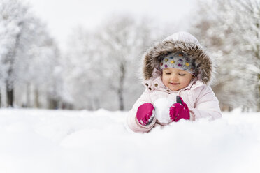 Niedliches kleines Mädchen spielt mit Schnee im Winter - DIGF05896
