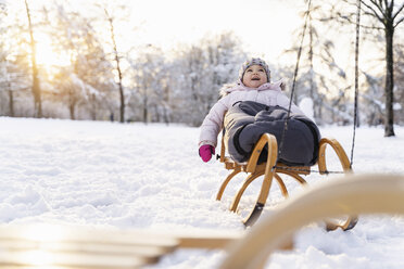 Glückliches Mädchen auf Schlitten in Winterlandschaft - DIGF05899