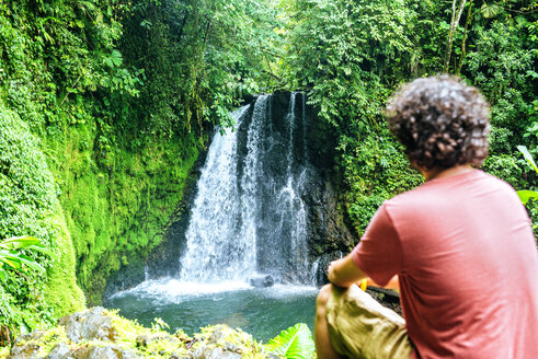 Costa Rica, sitzender Mann mit Blick auf einen Wasserfall - KIJF02326