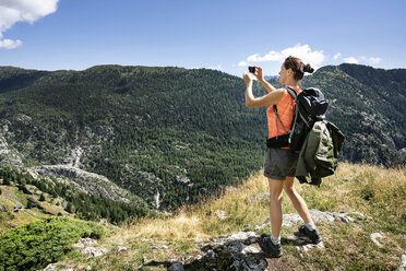 Schweiz, Wallis, Frau beim Fotografieren während einer Wanderung in den Bergen von Belalp zur Riederalp - DMOF00111