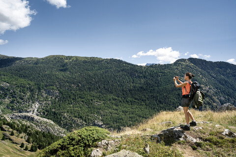 Schweiz, Wallis, Frau beim Fotografieren während einer Wanderung in den Bergen von Belalp zur Riederalp, lizenzfreies Stockfoto