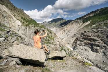 Schweiz, Wallis, Frau beim Fotografieren während einer Wanderung in den Bergen am Aletschgletscher - DMOF00114