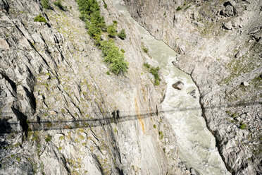 Schweiz, Wallis, Schatten von zwei Personen auf einer schwingenden Brücke über einer Schlucht - DMOF00117