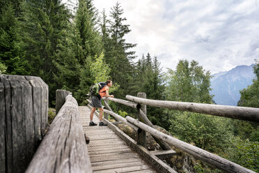 Schweiz, Wallis, Frau steht auf einer Holzbrücke während einer Wanderung auf dem Massaweg in den Bergen - DMOF00119
