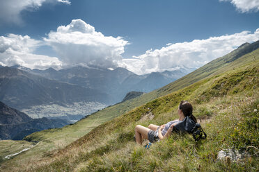 Schweiz, Wallis, Frau beim Wandern in den Bergen Richtung Foggenhorn auf Alpweide liegend - DMOF00130